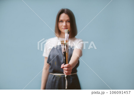 The artist holds brushes in her hands. Blurred background. 106091457