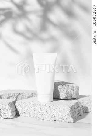 Empty white cream tube mockup on pumice stones for cosmetics product presentation. Minimal composition. Vertical studio photography. 106092657