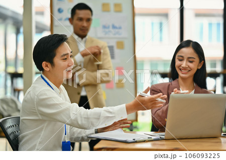 Asian male and female employee discussing project planning and advising on financial data report at office 106093225