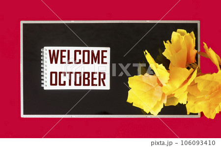 Note with welcome October text on notepad and black and red background with autumn decorations 106093410