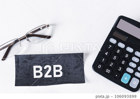 On the office table there is a calculator, a notebook with the text B2B and glasses.  106093899