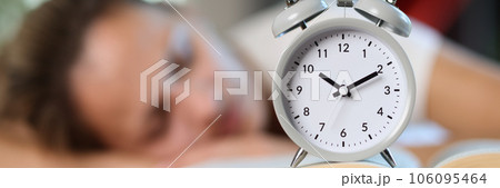 Overworked woman with book and alarm clock sleeps on office desk. Overworked woman with book and alarm clock sleeps on office desk. 106095464