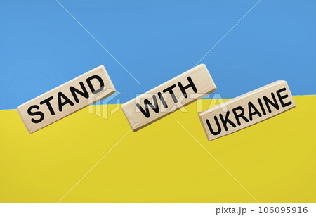 Wooden blocks with the text Stand for Ukraine on the table with the color of the flag of Ukraine 106095916