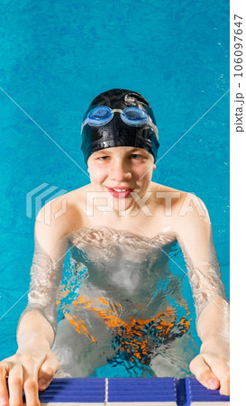 Preteen boy swimming in indoor pool during swim class 106097647