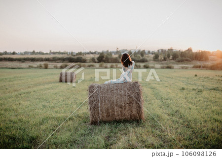 young naked girl with a sexy ass is sitting on haystack in field in summer. Added the effect of a small film grain 106098126