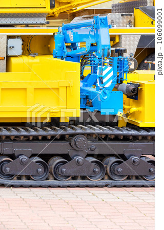 A blue hydraulic crane on a yellow crawler mobile construction platform. A blue hydraulic crane on a yellow crawler mobile construction platform. 106099001