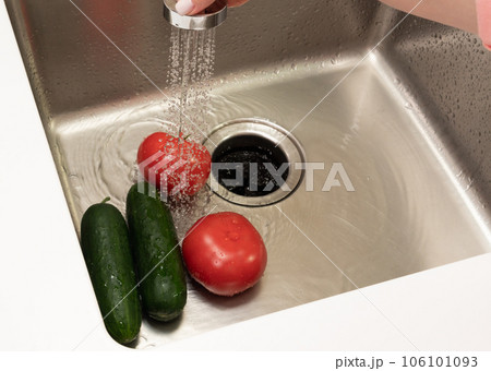 cucumbers and tomatoes in the sink are washed with a jet of cold water cucumbers and tomatoes in the sink are washed with a jet of cold water 106101093