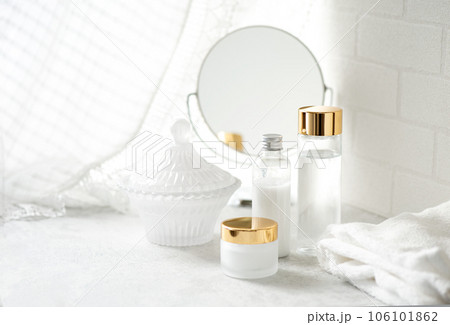 窓辺に置かれたスキンケア化粧品と白いタオルとミラー 106101862
