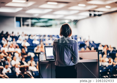 Female speaker giving a talk on corporate business conference. Unrecognizable people in audience at conference hall. Business and Entrepreneurship event 106102433