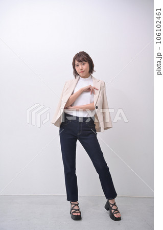 部屋の中の白い壁の前でジャケットを羽織ってポーズをとる女性 106102461