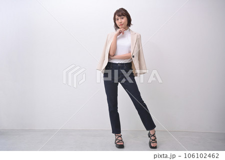部屋の中の白い壁の前でジャケットを羽織ってポーズをとる女性 106102462