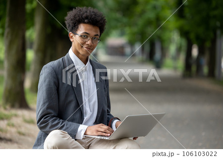 Curly-haired young digital nomad working in the park 106103022