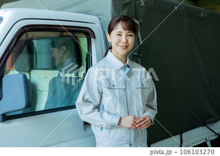 トラックの前に立つ作業着の女性 106103270