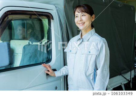トラックの前に立つ作業着の女性 106103349