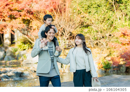秋の公園で紅葉を見ながら散歩する家族 106104305