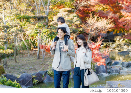 秋の公園で紅葉を見ながら散歩する家族 106104390