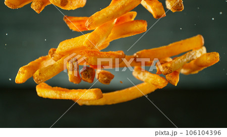 Freeze motion of flying french fries on dark background. Concept of junk unhealthy food, studio shot. Freeze motion of flying french fries on dark background. Concept of junk unhealthy food, studio shot. 106104396