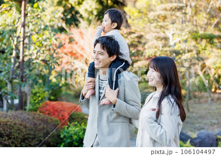 秋の公園で紅葉を見ながら散歩する家族 106104497