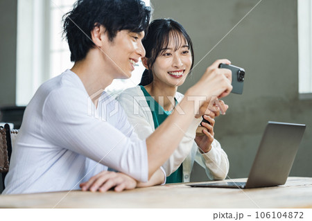 テーブルで一緒にスマホを見る男女カップル 106104872