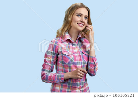 Portrait of young smiling blond woman is talking on mockup phone. Isolated on pastel blue background. Portrait of young smiling blond woman is talking on mockup phone. Isolated on pastel blue background. 106105521