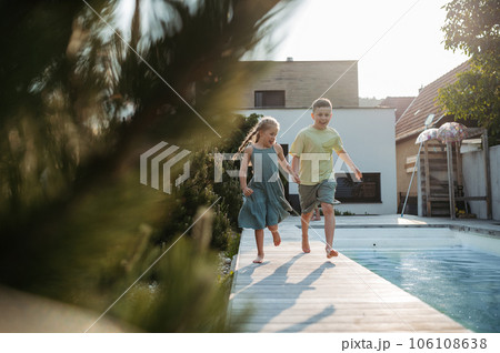 Young siblings running along swimming pool at home. Young siblings running along swimming pool at home. 106108638