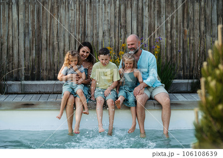 Cheerful family with three kids having fun together sitting by a pool. Cheerful family with three kids having fun together sitting by a pool. 106108639