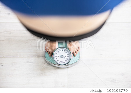 An obese woman stands on a scale and weighs more than 100 kilograms 106108770