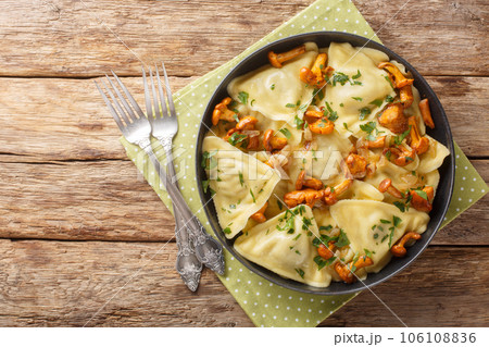 Italian pasta in the shape of a triangle stuffed with chanterelle mushrooms, onions and herbs close-up in a plate. Horizontal top view 106108836