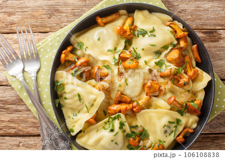 Triangoli Italian pasta in the shape of a triangle with forest mushrooms, onions and herbs close-up in a plate. Horizontal top view 106108838
