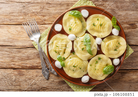 Cappellacci fresh filled pasta made with a delicious filling mozzarella and basil closeup on the plate on the wooden. Horizontal top view Cappellacci fresh filled pasta made with a delicious filling mozzarella and basil closeup on the plate on the wooden. Horizontal top view 106108851