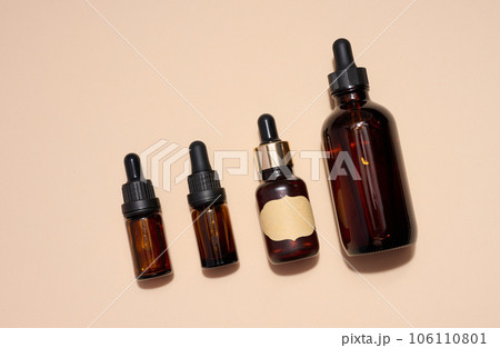 Brown glass bottle with a pipette on a beige background, a container for aromatic oils and cosmetics 106110801