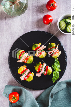 Appetizing sliders with vegetables and ham on a slate board top and vertical view 106111258