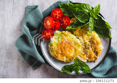 Close up of young cabbage steaks, tomatoes and basil on a plate top view 106111273