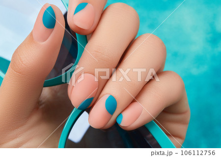 Close up womans hand with summer manicure on blue background. Manicure design trends 106112756