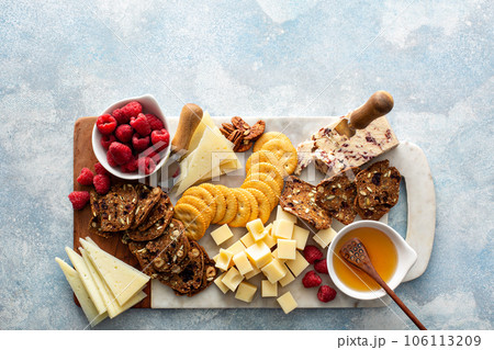 Cheese and snacks board with raspberry and crackers Cheese and snacks board with raspberry and crackers 106113209