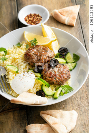 Herb turkey patties served with couscous and fresh salad Herb turkey patties served with couscous and fresh salad 106113395