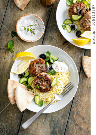 Herb turkey patties served with couscous and fresh salad 106113397
