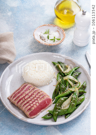 Seared tuna steak with white rice and green peas 106113542