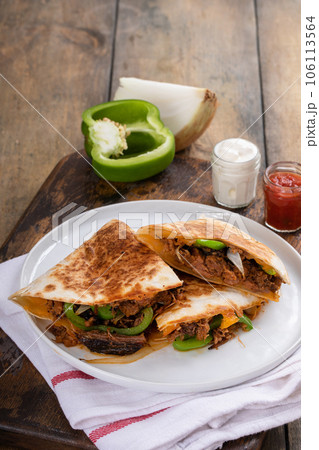 Brisket, peppers and onions quesadillas cut on a plate 106113564