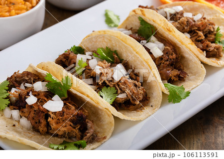Pork carnitas tacos on corn tortillas with rice and beans 106113591