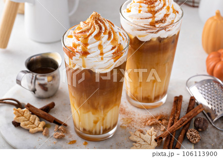 Iced pumpkin spice latte in tall glasses topped with whipped cream Iced pumpkin spice latte in tall glasses topped with whipped cream 106113900