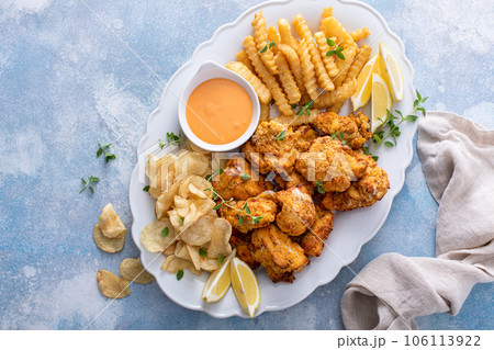 Fish and chips on a serving platter with dipping sauce 106113922