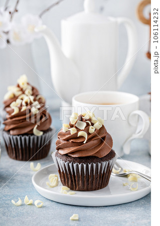 Dark chocolate cupcakes with whipped ganache frosting and white chocolate curls 106114232
