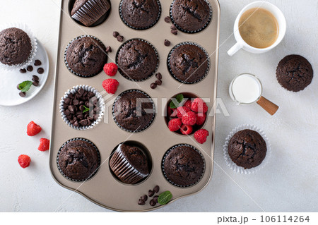 Chocolate muffins in a muffin pan with raspberries 106114264