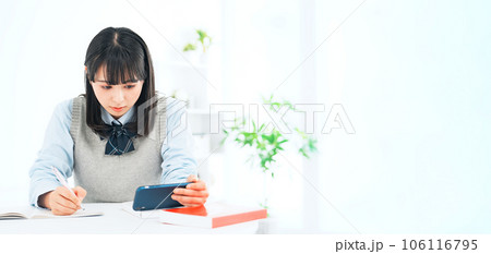 スマホを見ながら勉強する女子学生 106116795