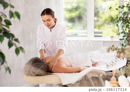 Young woman doing back massage to elderly woman Young woman doing back massage to elderly woman 106117314