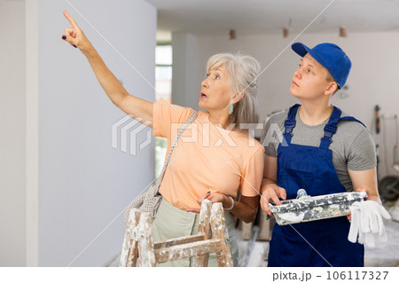 Senior woman discussing work details with teenager boy in constrcuction site 106117327