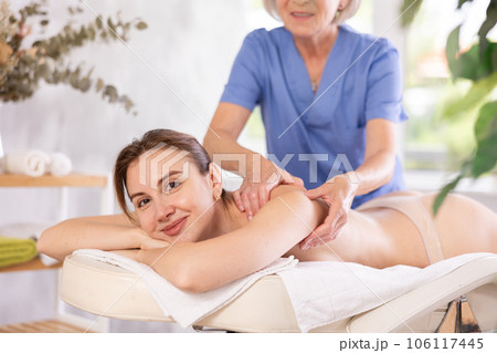 Young woman enjoying relaxing massage from professional female masseur Young woman enjoying relaxing massage from professional female masseur 106117445