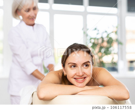 Relaxed young woman lying on couch during professional back massage Relaxed young woman lying on couch during professional back massage 106117558