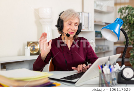 Office worker woman is working at a computer and talking by headset with client in office 106117629